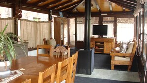 A cozy, rustic cabin interior with a dining area, seating, a fireplace, and a television. - Lezamakoetxe (Sopuerta)