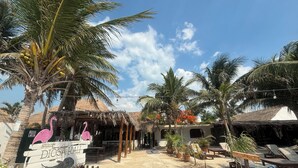 Un resort frente a la playa con construcciones de techo de paja, sillas de descanso y un letrero que dice "Diosakali".