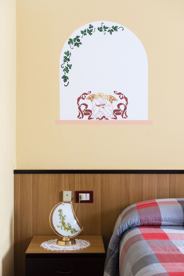 A bedroom with a bed, a nightstand, and a wall decoration.