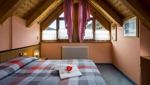 Un dormitorio con techo de madera, una cama con colcha a cuadros, una ventana con cortinas y un radiador.