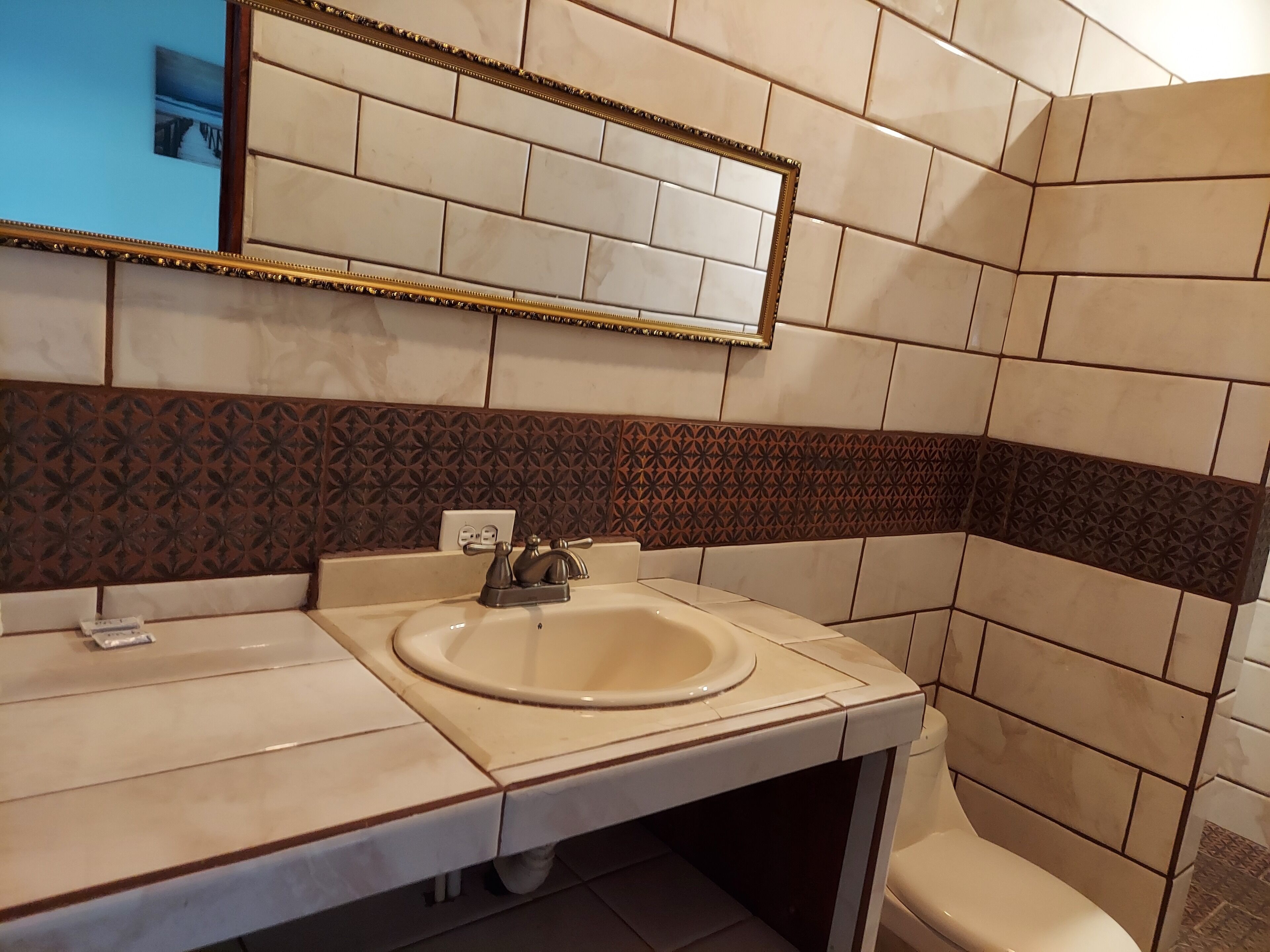 Une salle de bain avec un lavabo, un miroir et des toilettes.