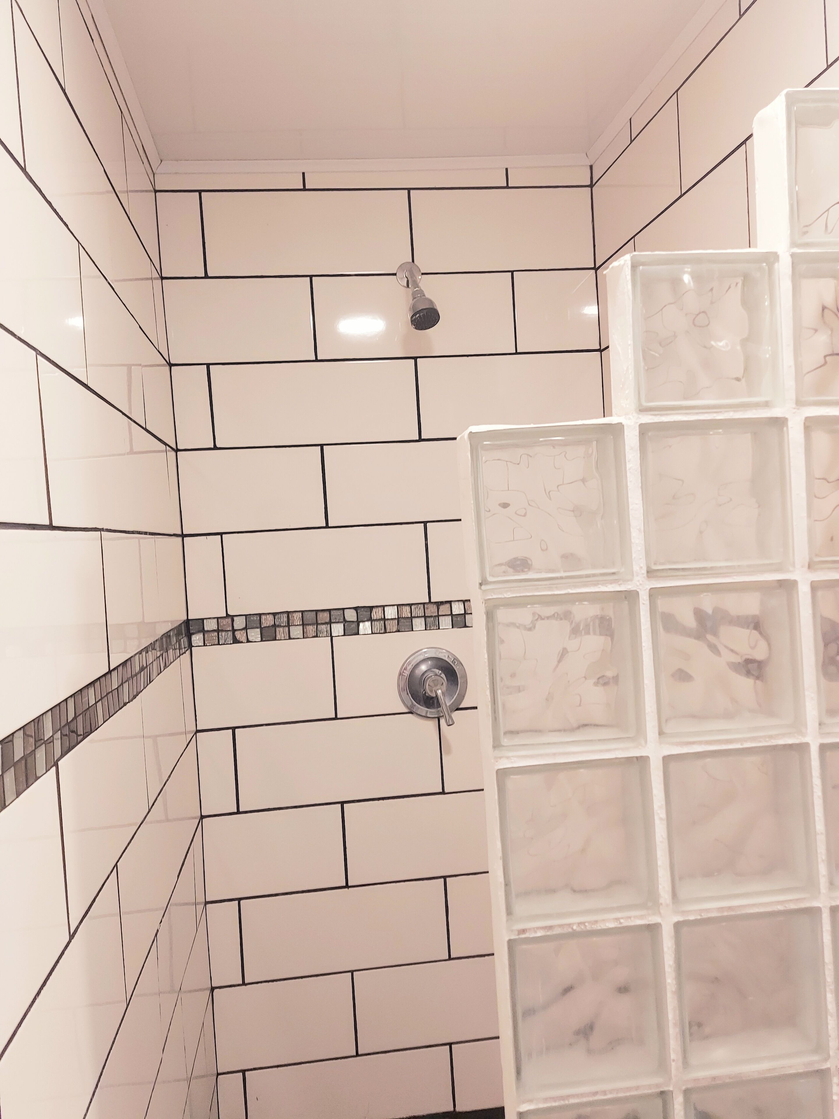 A bathroom with white subway tiles, a shower with a glass door, and a tiled shower area.