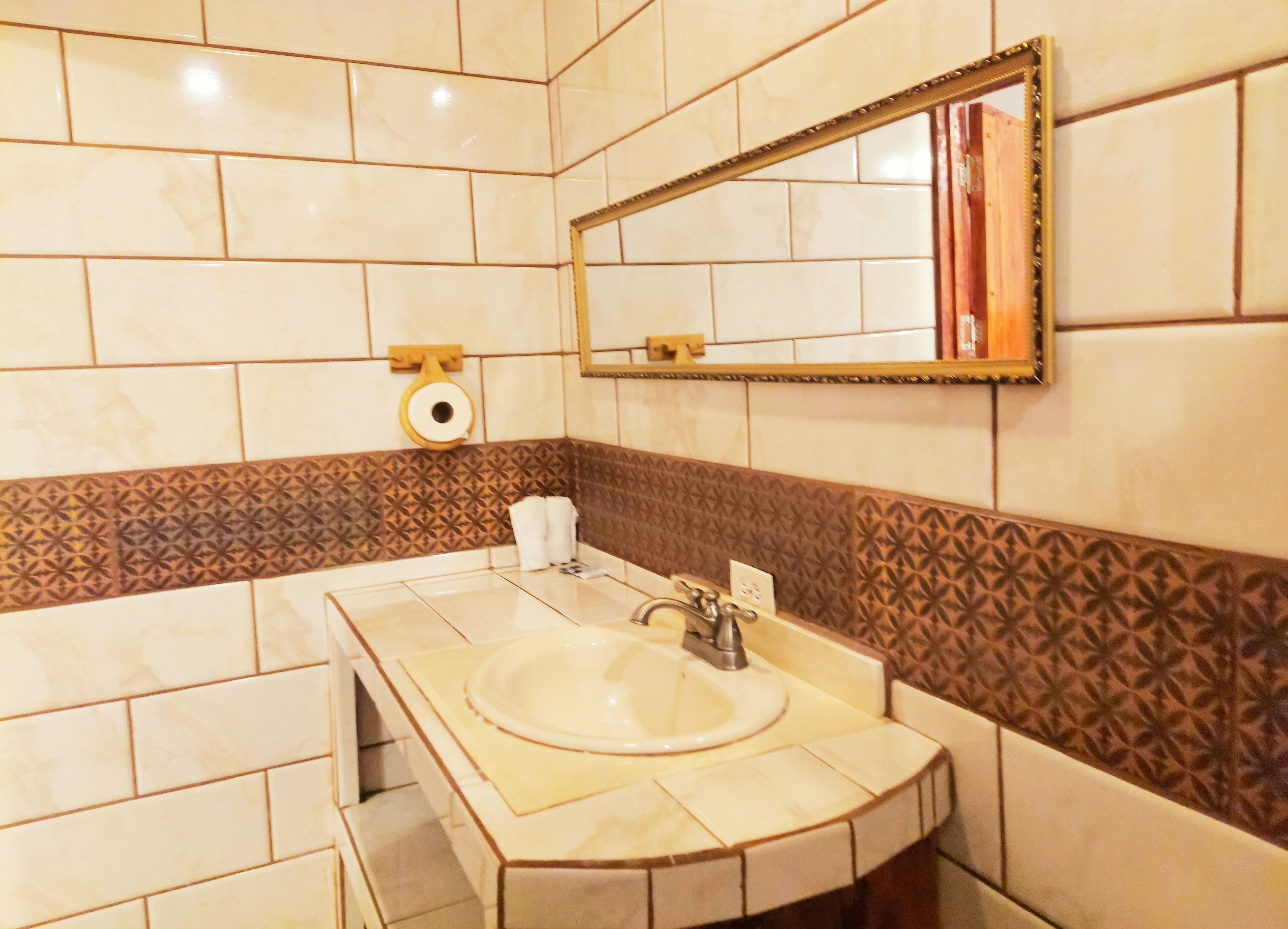 A bathroom with a sink, mirror, and patterned tiles.