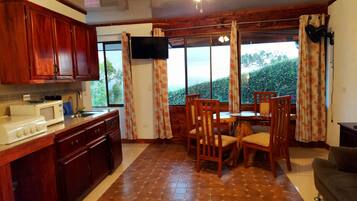 Una cocina con armarios de madera, microondas y comedor con mesa y sillas.