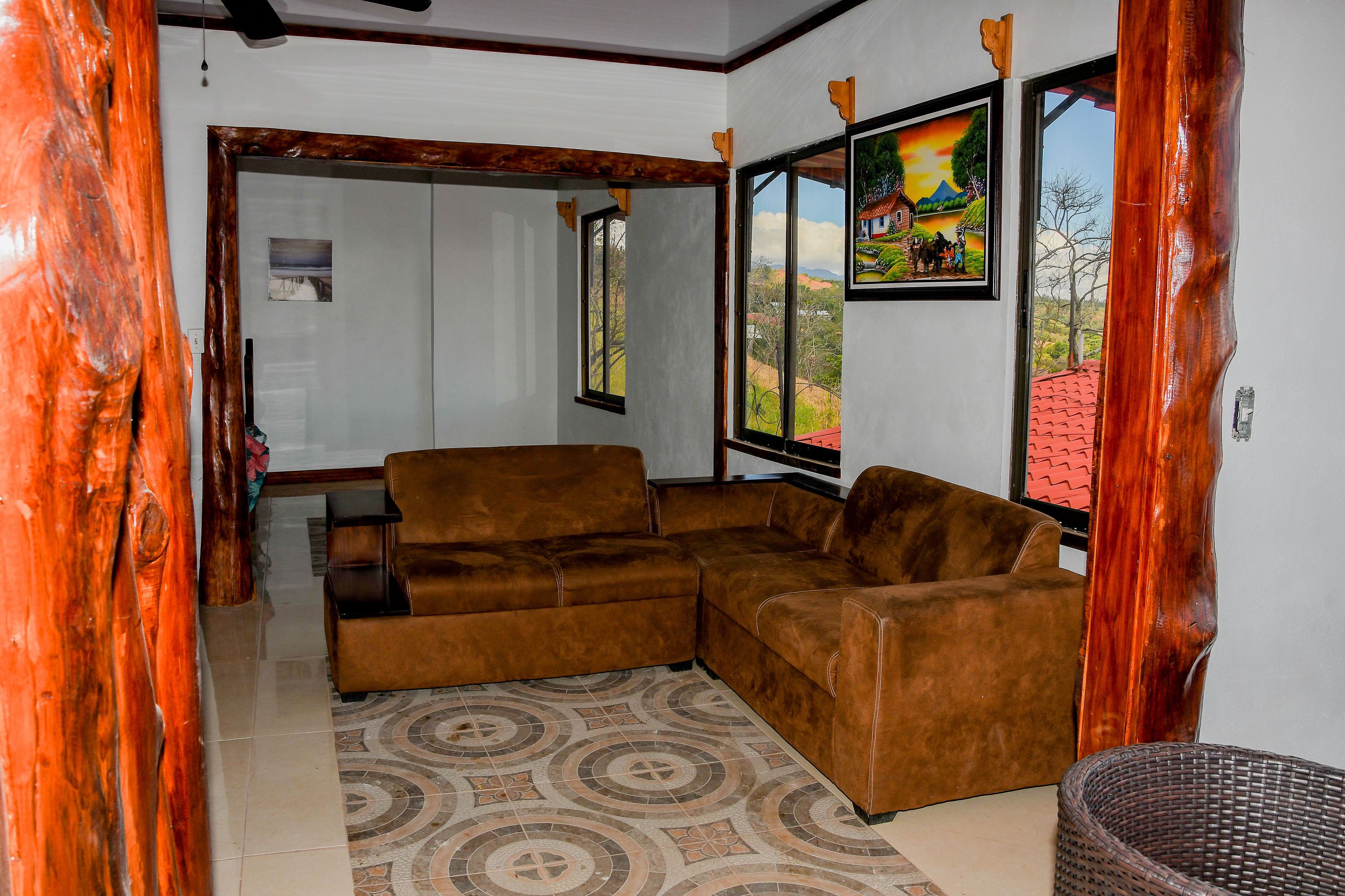 Una sala de estar con un sofá seccional de cuero marrón, un tapete estampado y una cesta de mimbre.