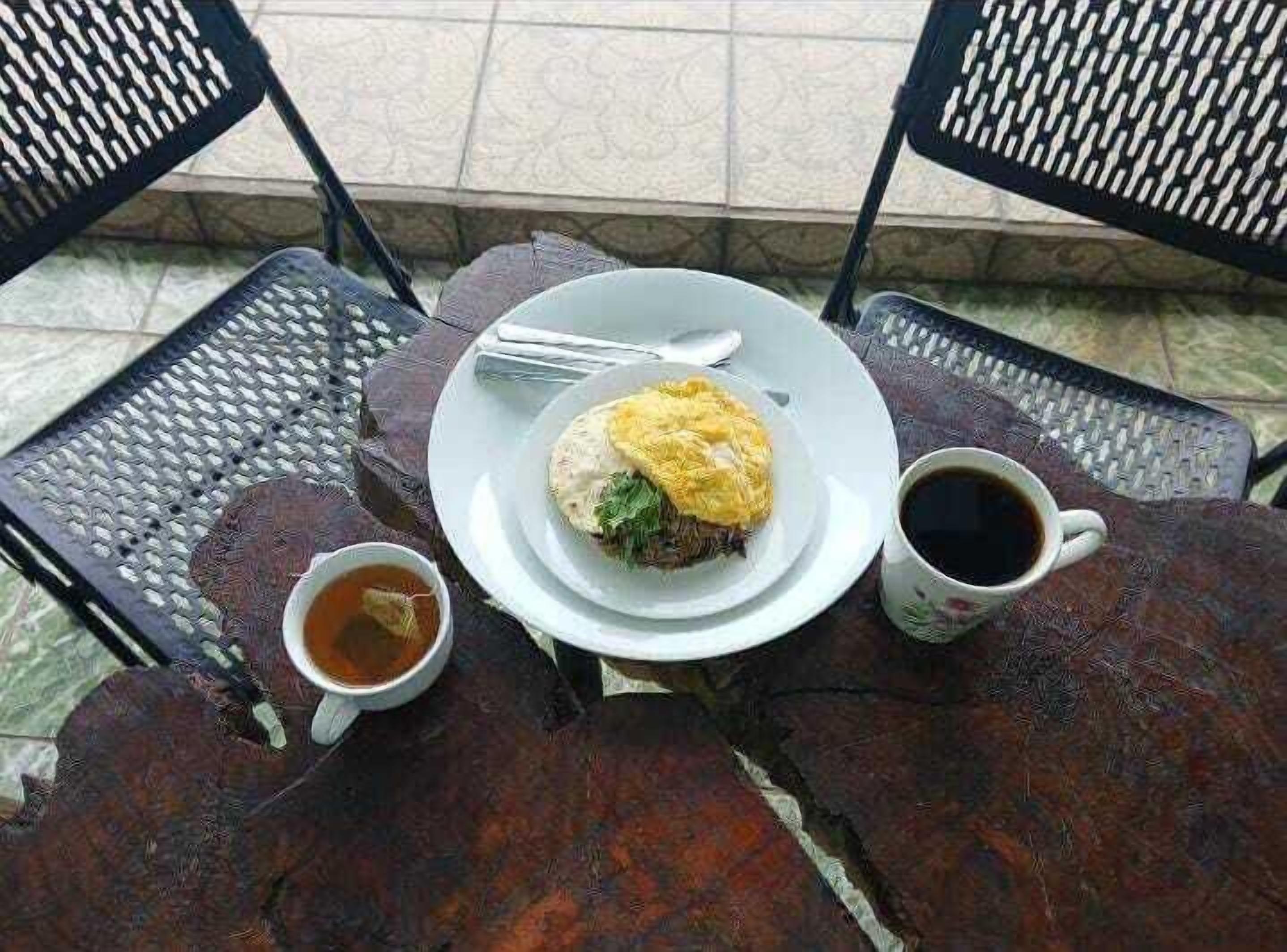 Una mesa con un plato de comida, una taza de café y una taza de té.