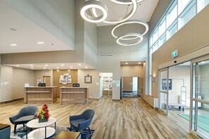 A hotel lobby with a reception desk, seating area, and a large window.