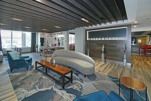 A modern interior with a sofa, chairs, a coffee table, and a fireplace. - Holiday Inn Hotel & Suites Calgary Airport North by IHG (Calgary)
