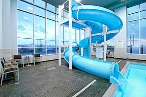A water slide in a large indoor pool area with high windows and seating. - Holiday Inn Hotel & Suites Calgary Airport North by IHG (Calgary)
