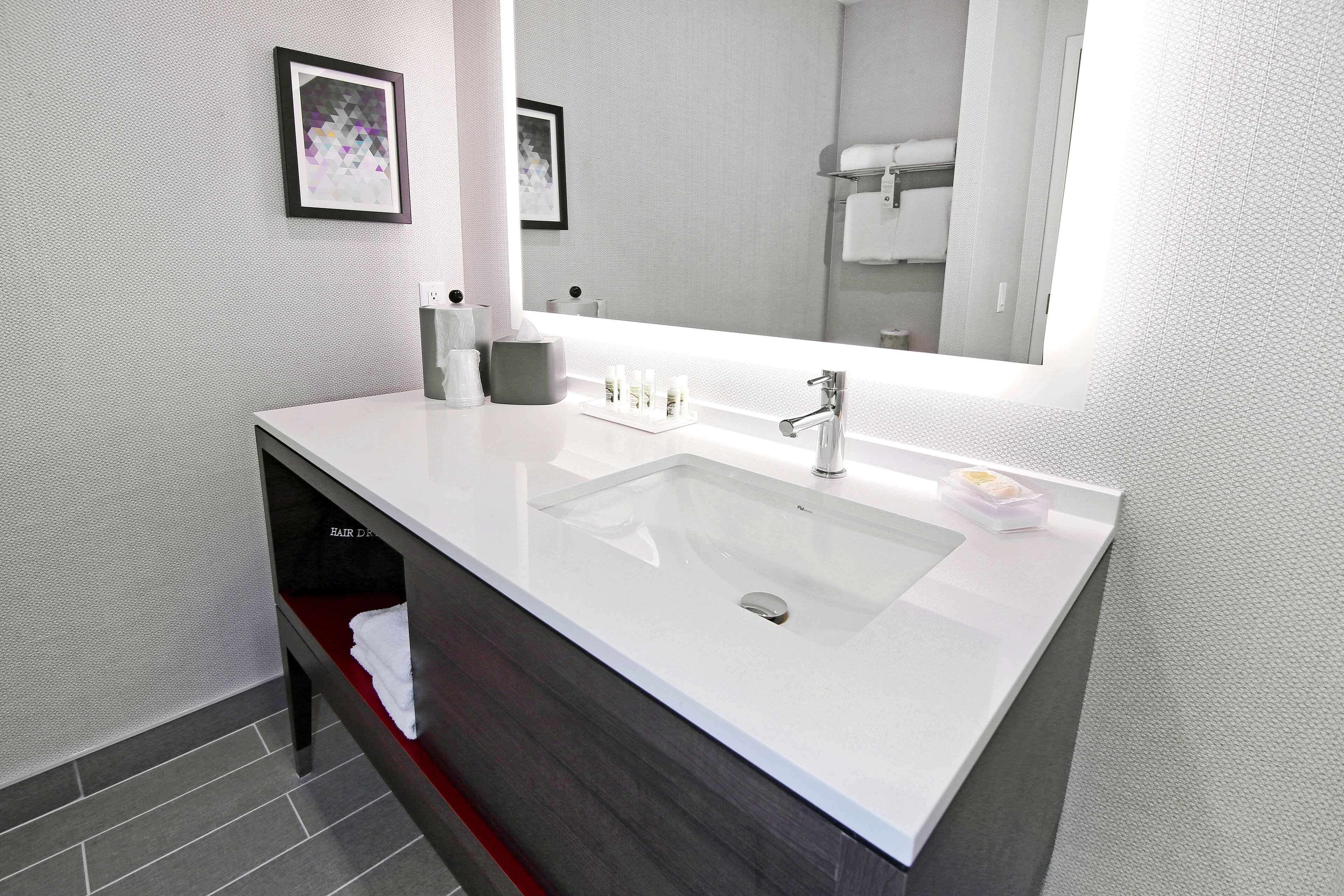 A modern bathroom with a large white sink, a mirror, and a towel rack.