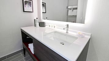A modern bathroom with a large white sink, a mirror, and a towel rack.