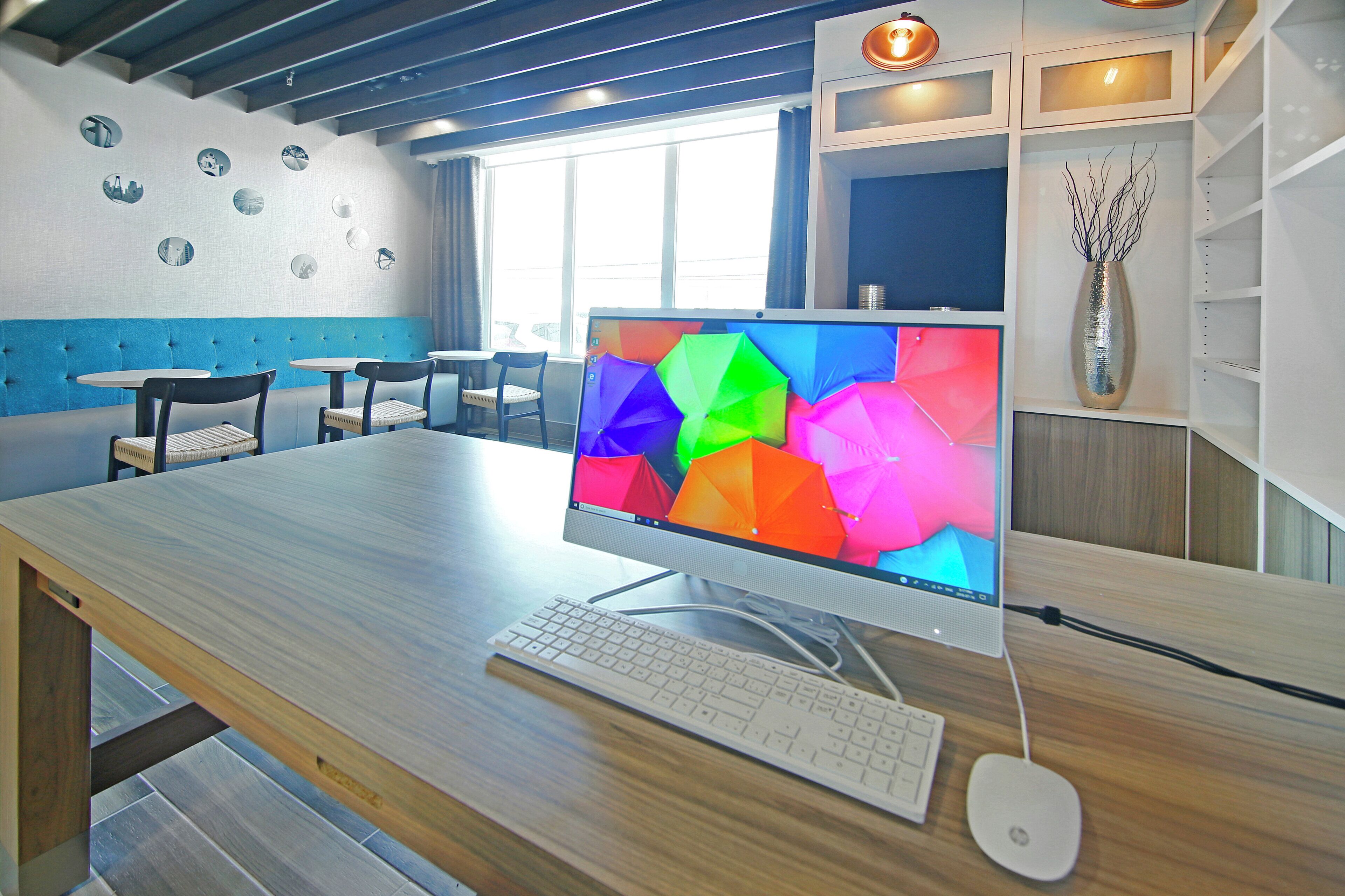 A modern office space with a desktop computer, keyboard, and mouse on a wooden desk.