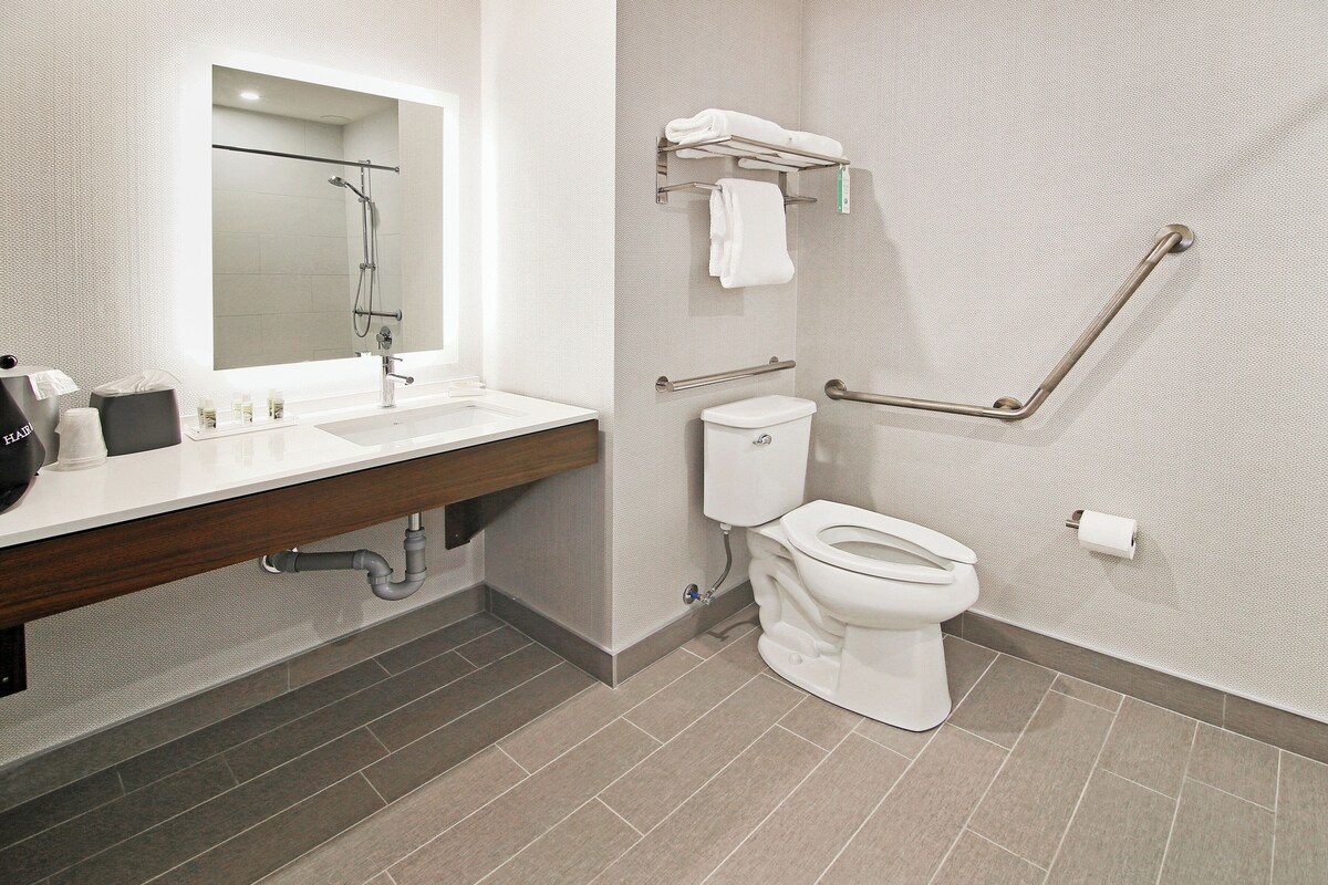 A modern bathroom with a sink, mirror, toilet, and shower.