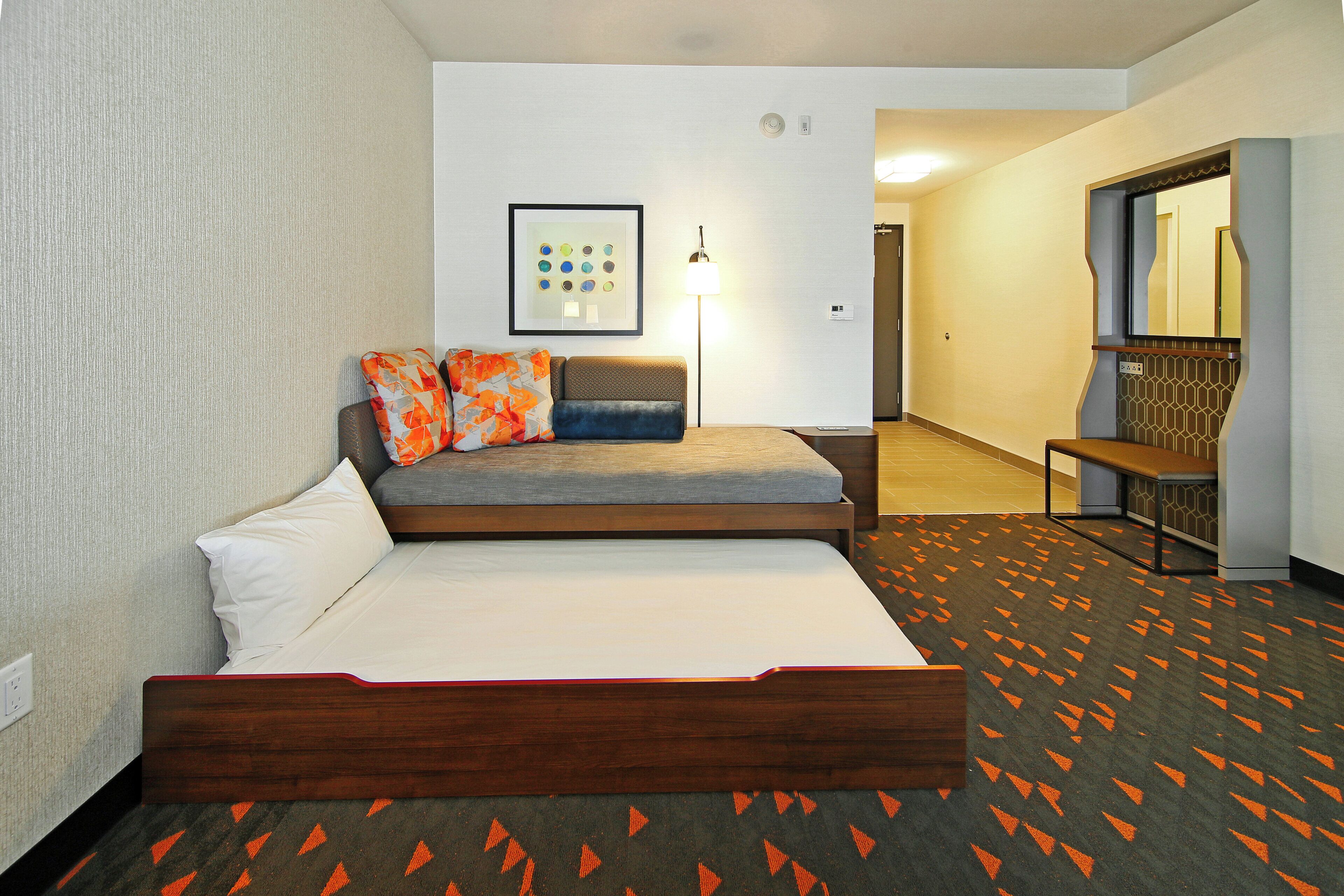 Una habitación de hotel con una cama, un sofá, una lámpara y un cuadro en la pared.