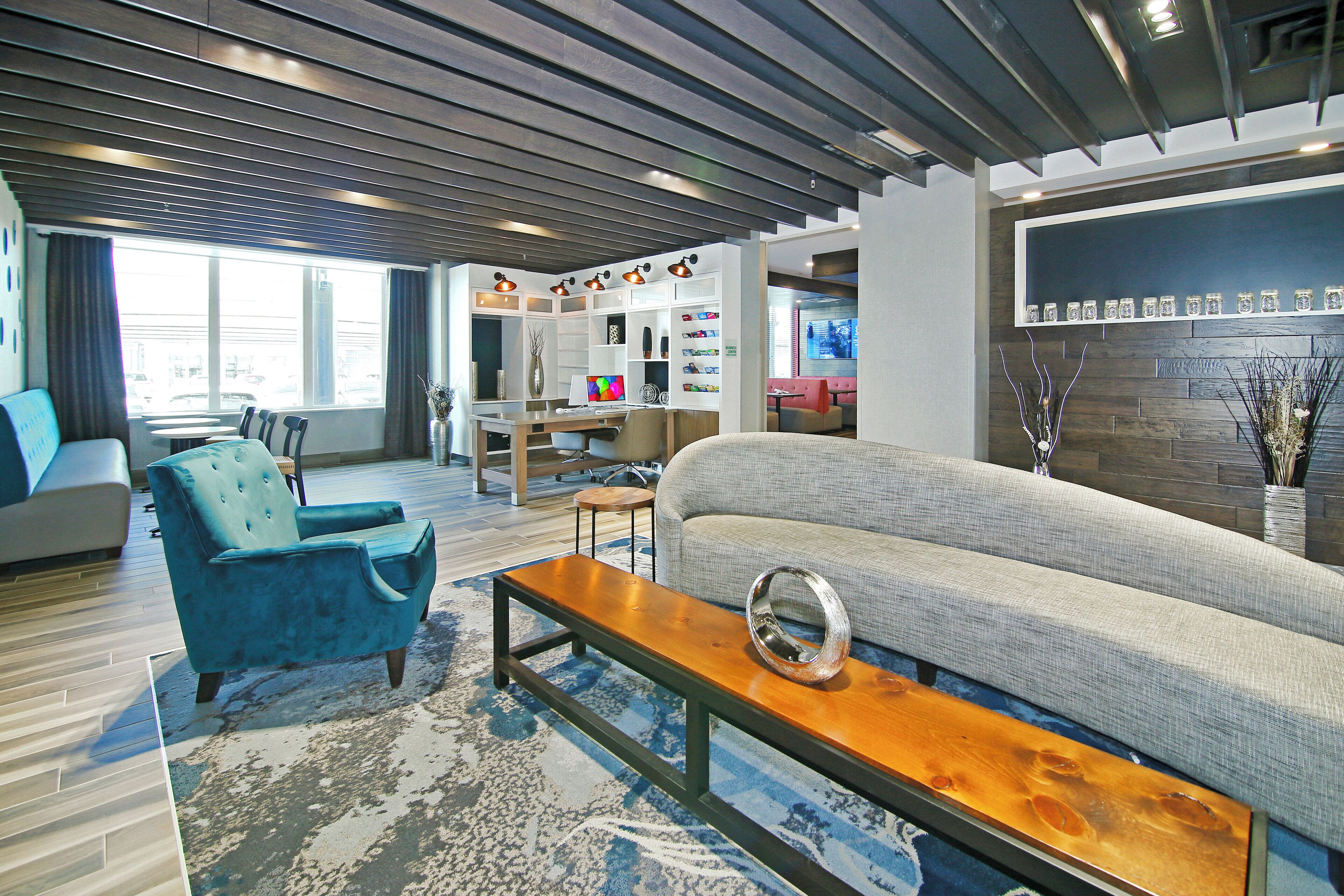 A modern living room with a sofa, a blue armchair, a wooden coffee table, and a dining area with a table and chairs.
