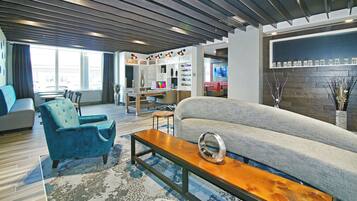 A modern living room with a sofa, a blue armchair, a wooden coffee table, and a dining area with a table and chairs.