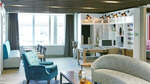 A modern living room with a sofa, armchair, and coffee table, a TV, and a bookshelf. - Holiday Inn Hotel & Suites Calgary Airport North by IHG (Calgary)