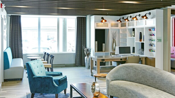 Una sala moderna con sofá, sillón, mesa de centro, televisor y estantería.