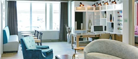 Ein modernes Wohnzimmer mit Sofa, Sessel und Couchtisch, einem Fernseher und einem Bücherregal.