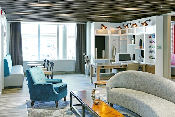 A modern living room with a sofa, armchair, and coffee table, a TV, and a bookshelf. - Holiday Inn Hotel & Suites Calgary Airport North by IHG (Calgary)