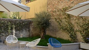 An outdoor seating area with two white and one blue chair, a small table, and a white umbrella. - Dimora 16 Rooms & Garden (Prato)
