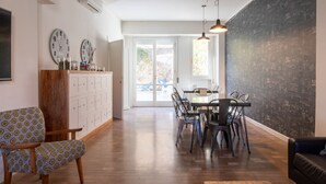 A dining area with a wooden cabinet, two wall clocks, a dining table with chairs, and a large chalkboard wall. - Dimora 16 Rooms & Garden (Prato)