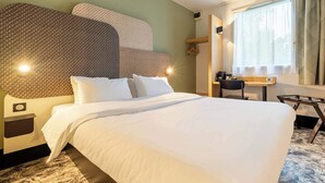 Une chambre d’hôtel avec un grand lit, un bureau, une chaise et une fenêtre avec des rideaux.