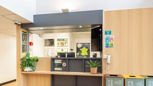 Un comptoir d’accueil avec un ordinateur, une plante et des poubelles de recyclage.