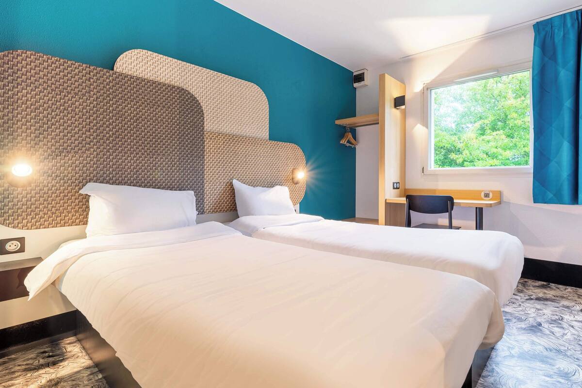 Een hotelkamer met een groot bed, een bureau en een raam met uitzicht op bomen.