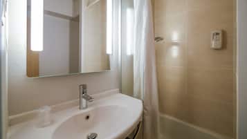 Un baño con un lavamanos blanco, un espejo, una cortina de ducha y un secador de manos.