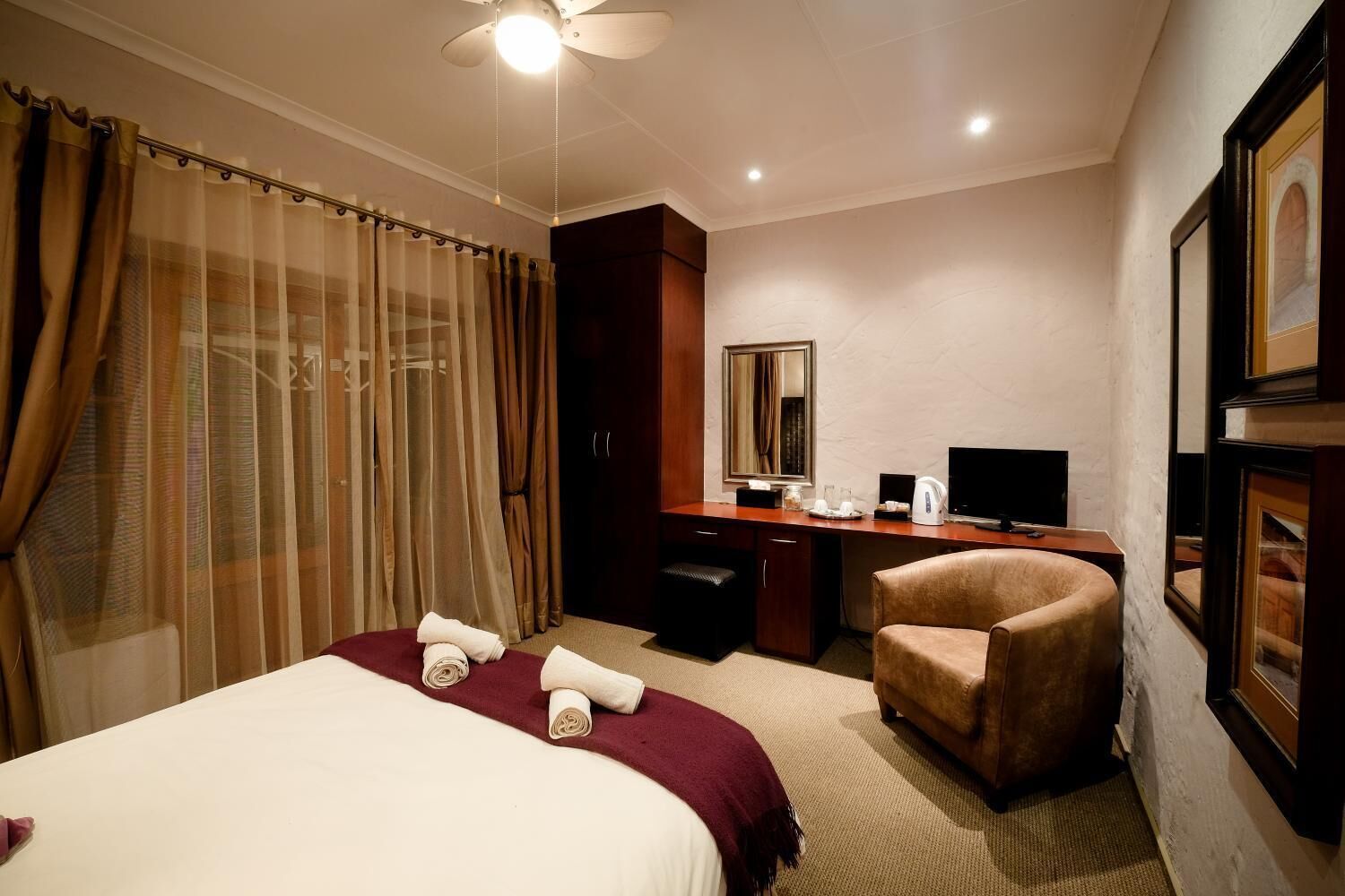 A hotel room with a bed, a desk, a chair, a television, and a mirror.