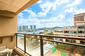 Un balcon offrant une vue sur le paysage urbain, avec des bâtiments et une étendue d’eau.