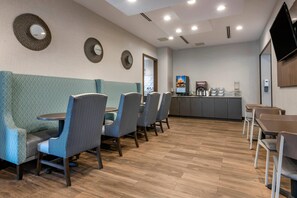 Un café moderno con mesas, una máquina de café y un televisor.