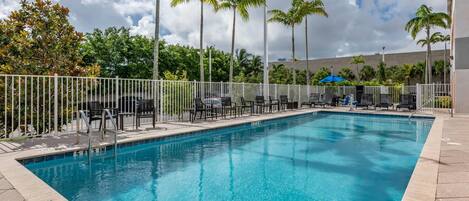 A rectangular swimming pool with clear blue water, surrounded by a white fence.