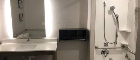 Un baño moderno con lavamanos, espejo y zona de ducha.