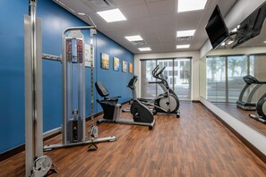 A gym with exercise equipment, a TV, and large windows. - Comfort Suites Fort Lauderdale Airport & Cruise Port (Dania Beach)