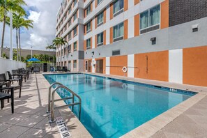 A swimming pool with a 5ft3in depth marker, surrounded by lounge chairs and a building with orange and grey walls. - Comfort Suites Fort Lauderdale Airport & Cruise Port (Dania Beach)