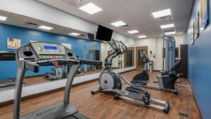 Un gimnasio con cintas de correr, elípticas y máquinas de pesas.