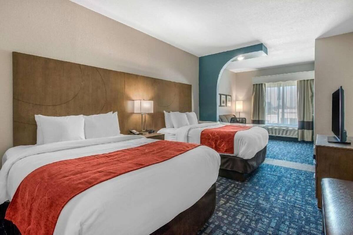 A hotel room with two beds, a TV, and a window with curtains.
