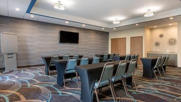 A conference room with a large table, chairs, a flat-screen TV, and a whiteboard.