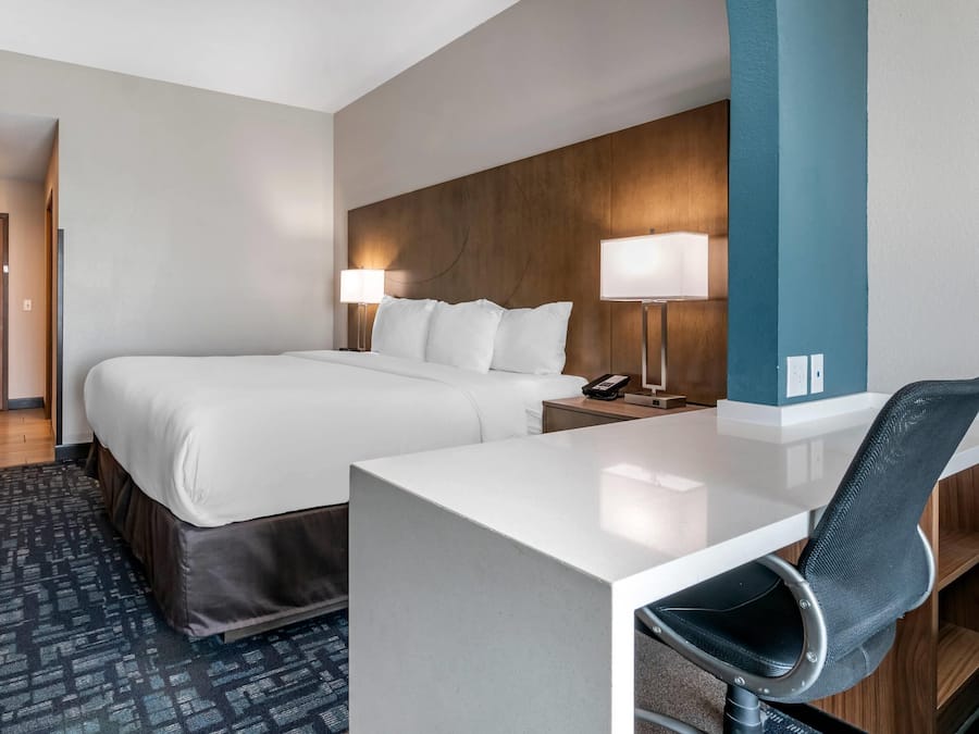 A hotel room with a bed, bedside tables, a desk, and a chair.