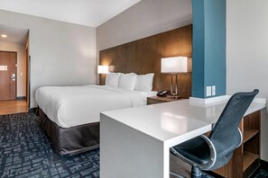 Una habitación de hotel con cama, mesitas de noche, un escritorio y una silla.