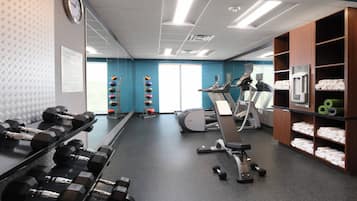 A fitness center with dumbbells, a treadmill, and exercise balls.