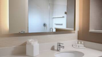 Un baño moderno con un lavamanos blanco, un espejo y un perchero para toallas.