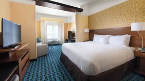 Una habitación de hotel con una cama grande, televisión, escritorio y una silla.