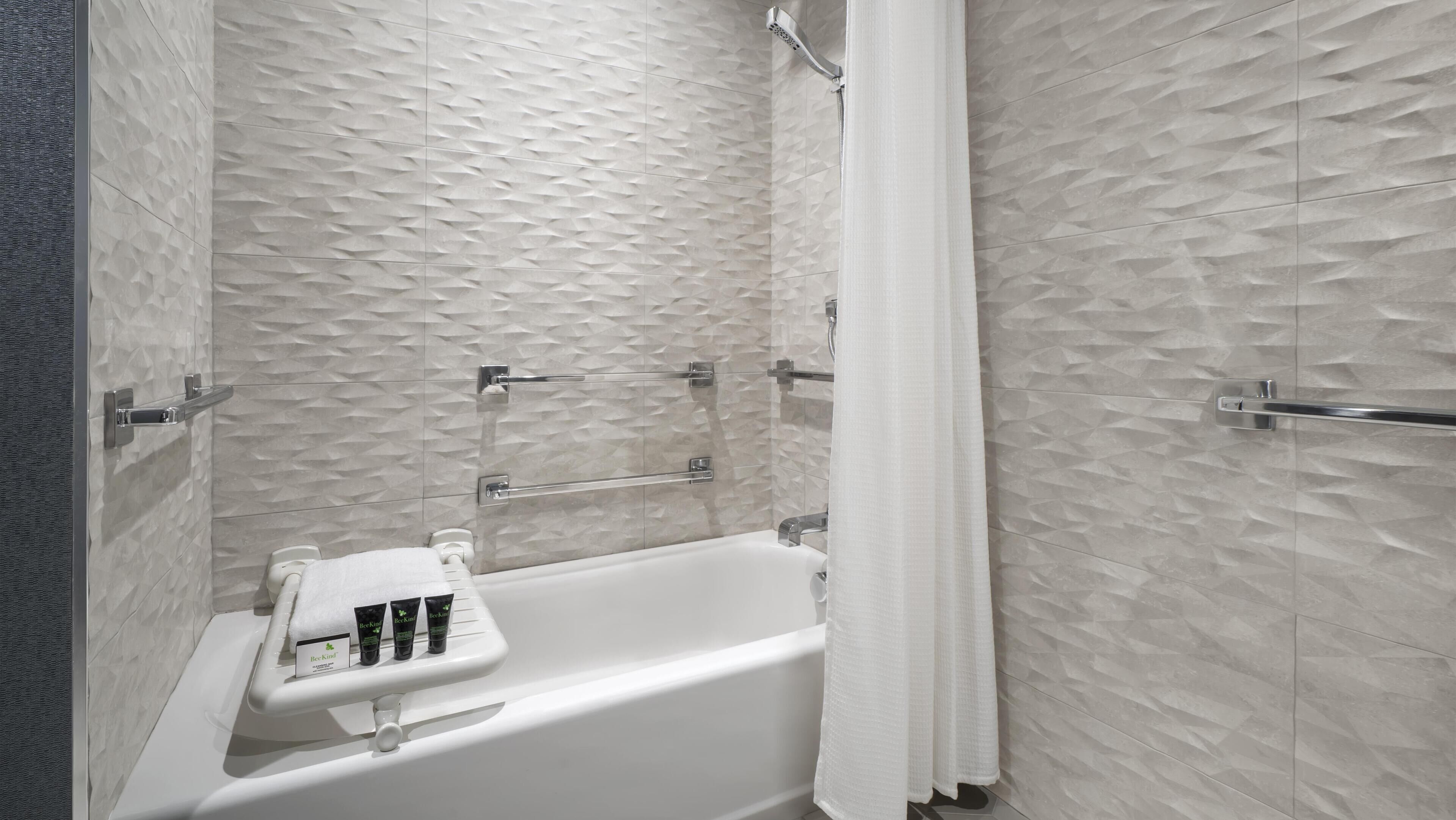 A modern bathroom with a bathtub, a towel rack, and a shelf with toiletries.