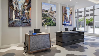 A modern hotel room with a large bed, a sofa, a small table, and a TV. The room has a view of the sea and a building across the water. at Hyatt Centric Brickell Miami