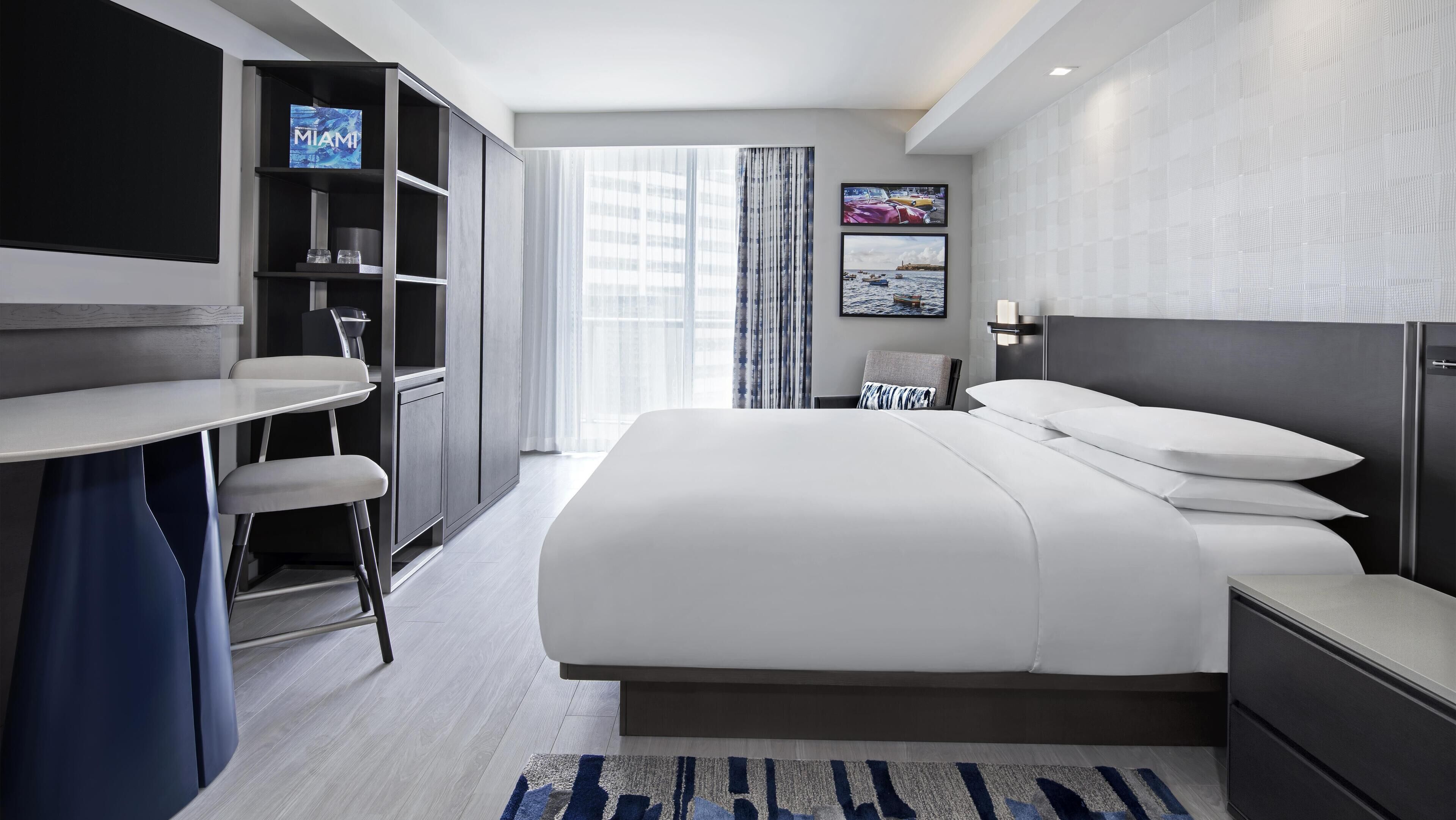 Une chambre d’hôtel moderne, dotée d’un grand lit, d’un bureau et d’une télévision.