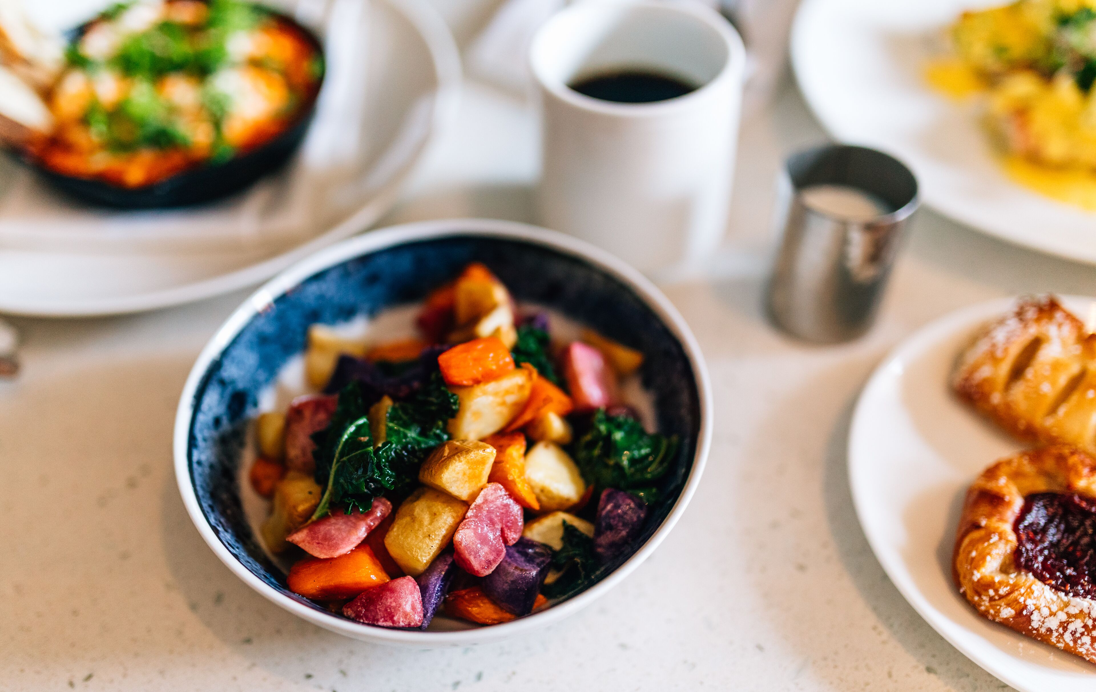 Una mesa de comedor con un tazón de vegetales mixtos y una taza de café.
