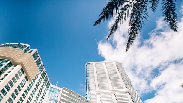 A modern hotel with a curved facade, multiple balconies, and large windows.